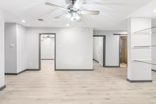 empty room featuring light hardwood / wood-style floors, a barn door, and ceiling fan