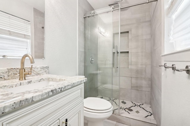 bathroom with toilet, vanity, and a shower with shower door