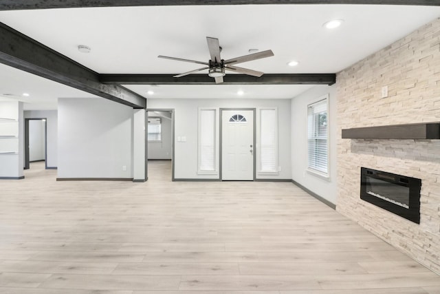 unfurnished living room with beamed ceiling, ceiling fan, a fireplace, and light hardwood / wood-style floors