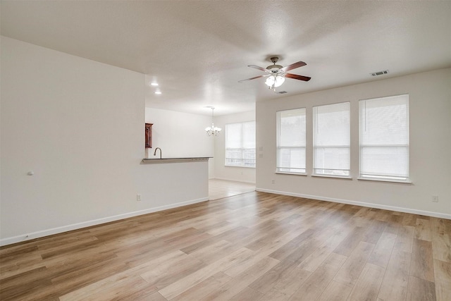 408 Elk Run Dr, Fort Worth, TX 76140 - unfurnished living room with sink, ceiling fan with notable chandelier, and light hardwood / wood-style flooring