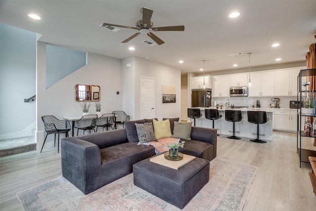 living room with ceiling fan and light hardwood / wood-style flooring