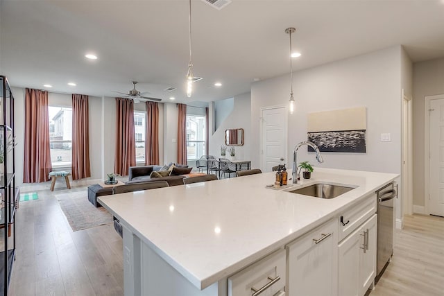 kitchen with a center island with sink, sink, pendant lighting, and white cabinets