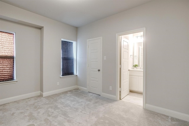 unfurnished bedroom featuring connected bathroom and light carpet