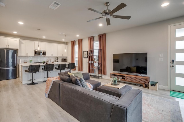 living room with ceiling fan and light wood-type flooring