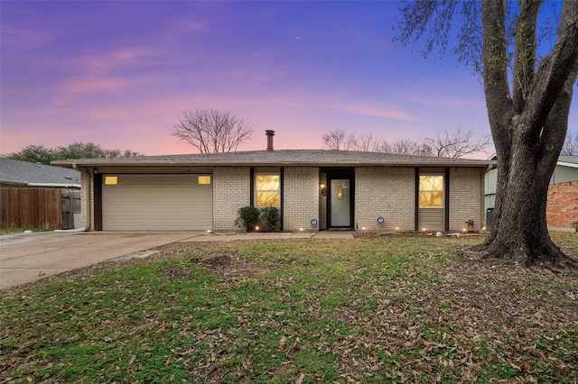 view of front facade featuring driveway, a lawn, an attached garage, fence, and brick siding