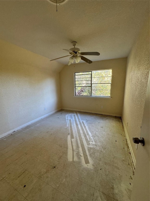 spare room featuring ceiling fan, lofted ceiling, and a textured ceiling