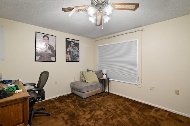 office area featuring a textured ceiling, dark carpet, and ceiling fan