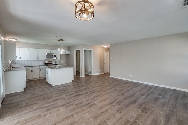 kitchen featuring sink, hanging light fixtures, stainless steel appliances, a center island, and white cabinets