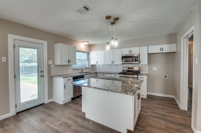 kitchen featuring white cabinetry, sink, hanging light fixtures, a center island, and stainless steel appliances