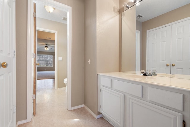 bathroom featuring vanity, ceiling fan, a textured ceiling, and toilet