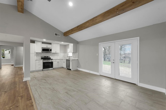 kitchen featuring sink, white cabinetry, backsplash, stainless steel appliances, and beamed ceiling