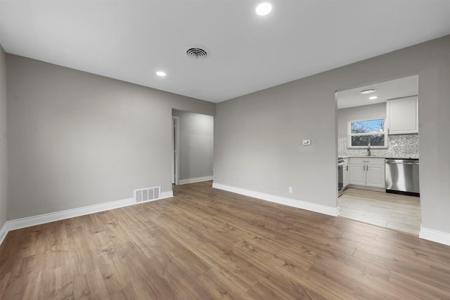 spare room with sink and light hardwood / wood-style flooring