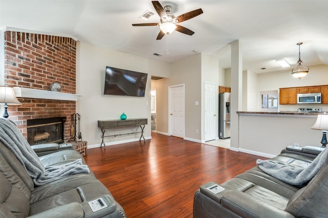 living room featuring ceiling fan, a brick fireplace, vaulted ceiling, and light hardwood / wood-style flooring