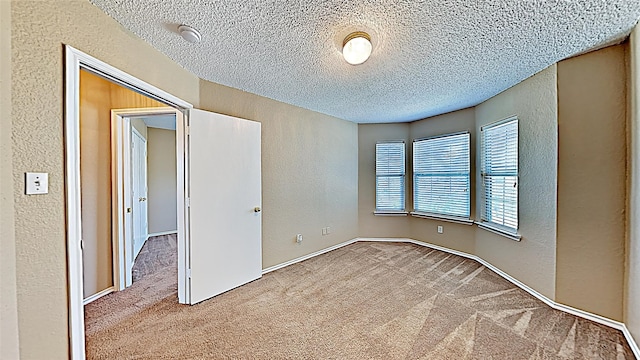 carpeted empty room featuring a textured ceiling