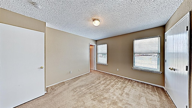 unfurnished bedroom with light colored carpet, a closet, and a textured ceiling