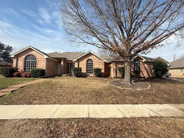 single story home with a garage, a front yard, and brick siding