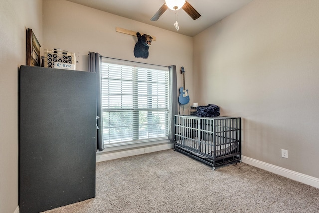 bedroom with a crib, ceiling fan, and carpet