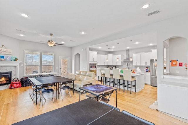 interior space with ceiling fan, a fireplace, and light wood-type flooring