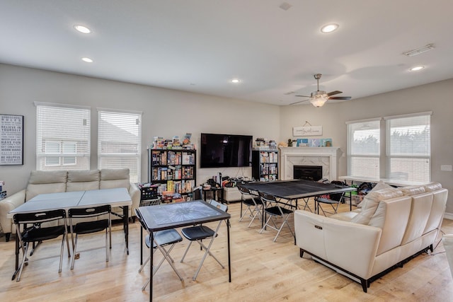 living room with ceiling fan, a premium fireplace, and light hardwood / wood-style floors