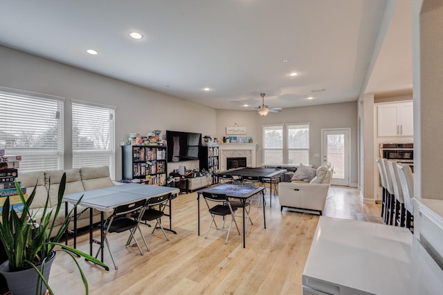 dining space with ceiling fan, light wood-type flooring, and a fireplace