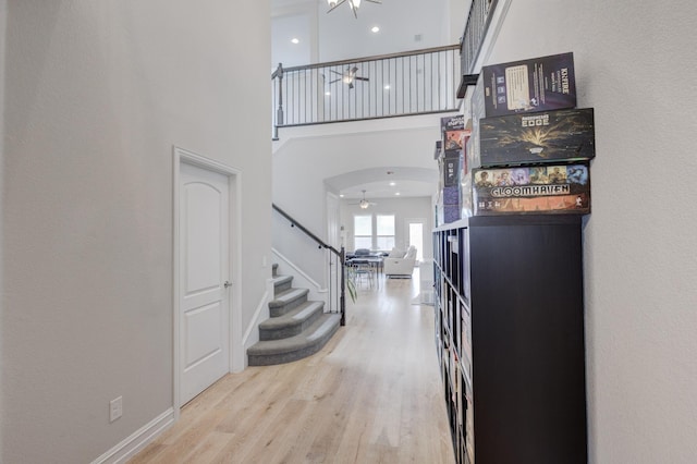 foyer entrance featuring a high ceiling, ceiling fan, and light hardwood / wood-style flooring