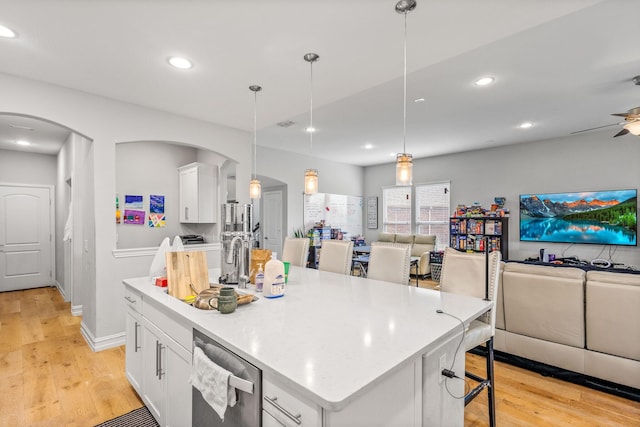 kitchen featuring hanging light fixtures, a center island with sink, white cabinets, and a kitchen bar