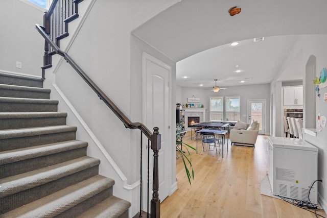 stairs with hardwood / wood-style floors and ceiling fan