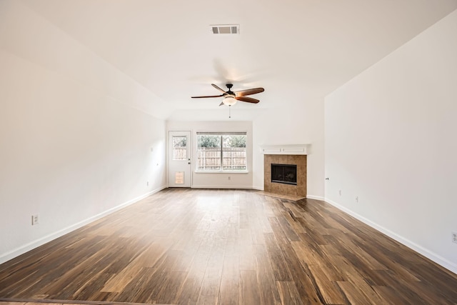 unfurnished living room featuring dark hardwood / wood-style flooring, a tile fireplace, and ceiling fan