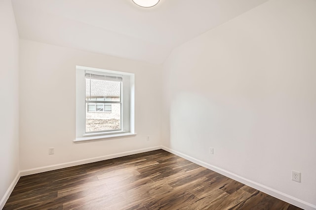 spare room featuring lofted ceiling and dark hardwood / wood-style floors