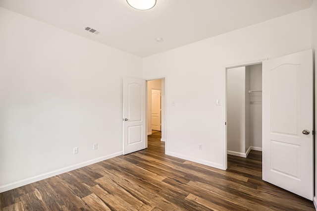 unfurnished bedroom with a walk in closet, dark hardwood / wood-style flooring, and a closet