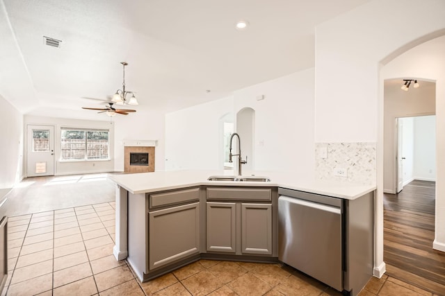 kitchen with gray cabinets, a fireplace, sink, stainless steel dishwasher, and ceiling fan