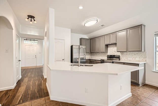 kitchen featuring sink, gray cabinets, appliances with stainless steel finishes, tasteful backsplash, and an island with sink