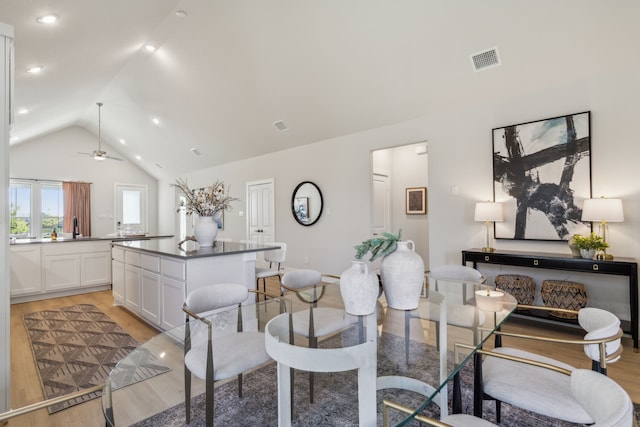 dining room with vaulted ceiling, sink, ceiling fan, and light hardwood / wood-style flooring