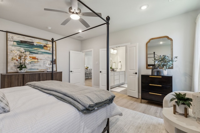 bedroom featuring ceiling fan, ensuite bath, and light wood-type flooring