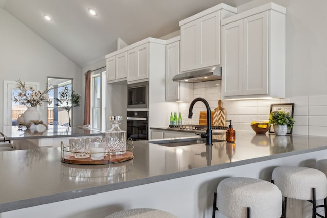 kitchen with white cabinetry, decorative backsplash, a kitchen breakfast bar, and kitchen peninsula