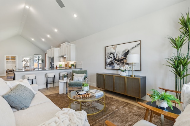 living room with lofted ceiling, sink, and light hardwood / wood-style flooring