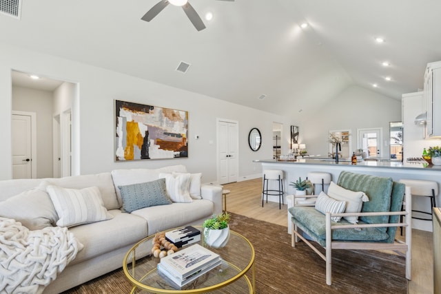 living room featuring ceiling fan, high vaulted ceiling, and light hardwood / wood-style floors