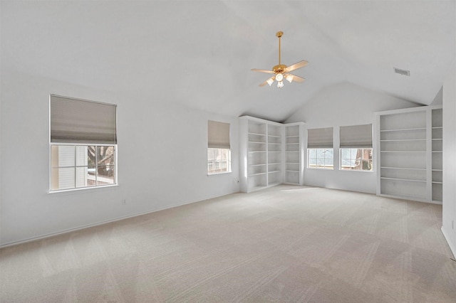 interior space with built in shelves, ceiling fan, plenty of natural light, and vaulted ceiling