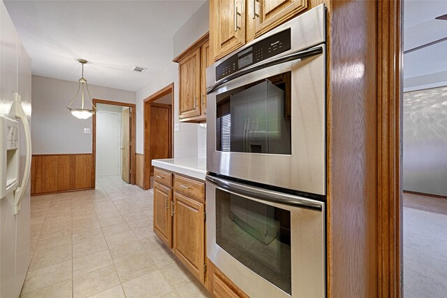 kitchen with white refrigerator with ice dispenser, light countertops, visible vents, stainless steel double oven, and wainscoting