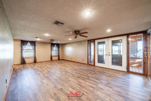 empty room with hardwood / wood-style flooring, ceiling fan, a textured ceiling, and french doors