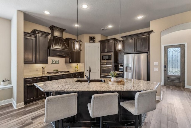 kitchen featuring pendant lighting, sink, appliances with stainless steel finishes, a kitchen island with sink, and tasteful backsplash