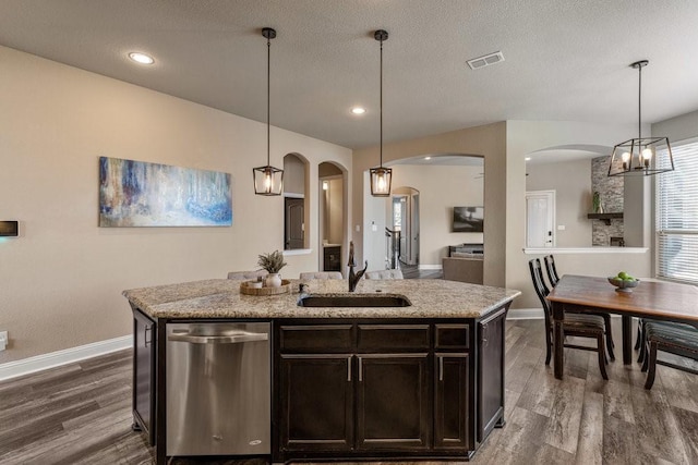 kitchen featuring a kitchen island with sink, sink, pendant lighting, and dishwasher