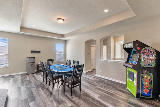 dining space featuring a raised ceiling, hardwood / wood-style floors, and a textured ceiling