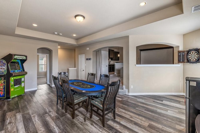 dining space featuring a raised ceiling and dark wood-type flooring