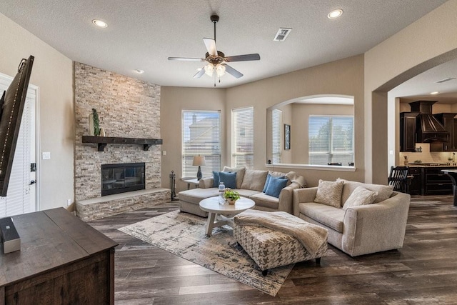 living room with plenty of natural light, a textured ceiling, a fireplace, and dark hardwood / wood-style flooring