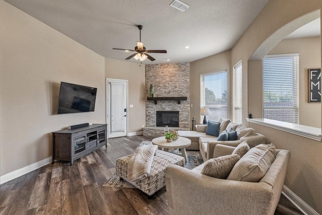 living room with ceiling fan, a fireplace, dark hardwood / wood-style flooring, and a textured ceiling