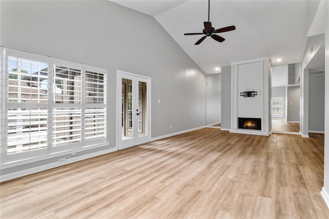 unfurnished living room featuring french doors, high vaulted ceiling, ceiling fan, a fireplace, and light hardwood / wood-style floors