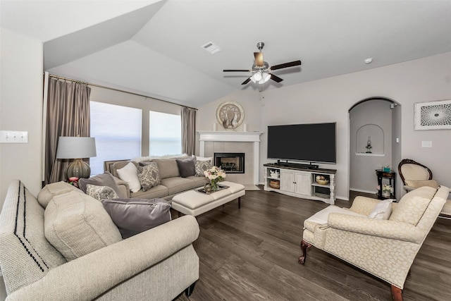 living room featuring vaulted ceiling, ceiling fan, a tiled fireplace, and dark hardwood / wood-style floors