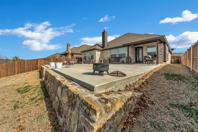 back of house with central air condition unit, a patio area, and a fire pit