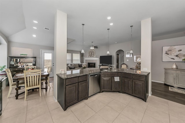 kitchen with stainless steel dishwasher, ceiling fan, dark brown cabinets, and dark stone counters